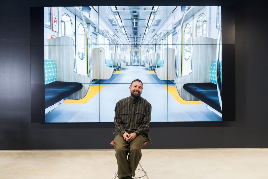 Nozue in front an image showing the interior of new Series 3000